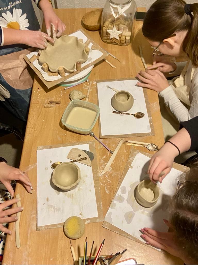 Artist guiding guests at a cozy ceramics studio table